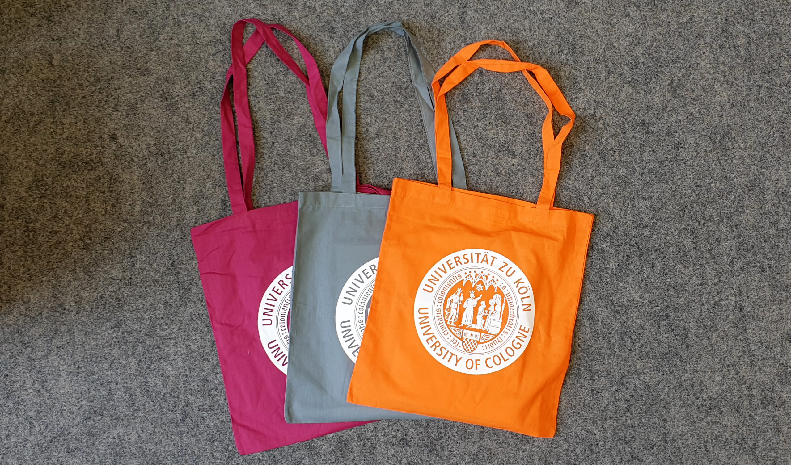 Three bags with the emblem of the University of Cologne on them