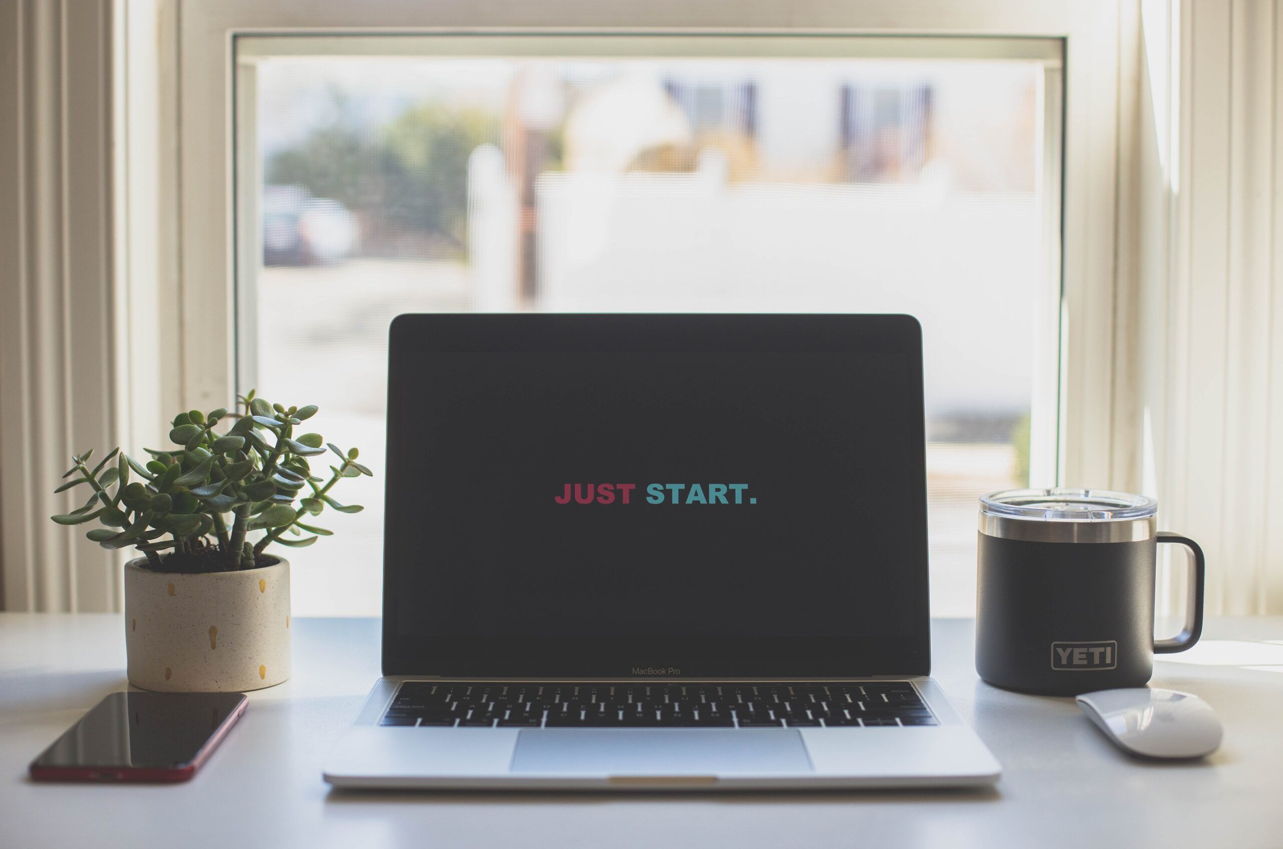 A laptop with the words "Just Start." on the screen