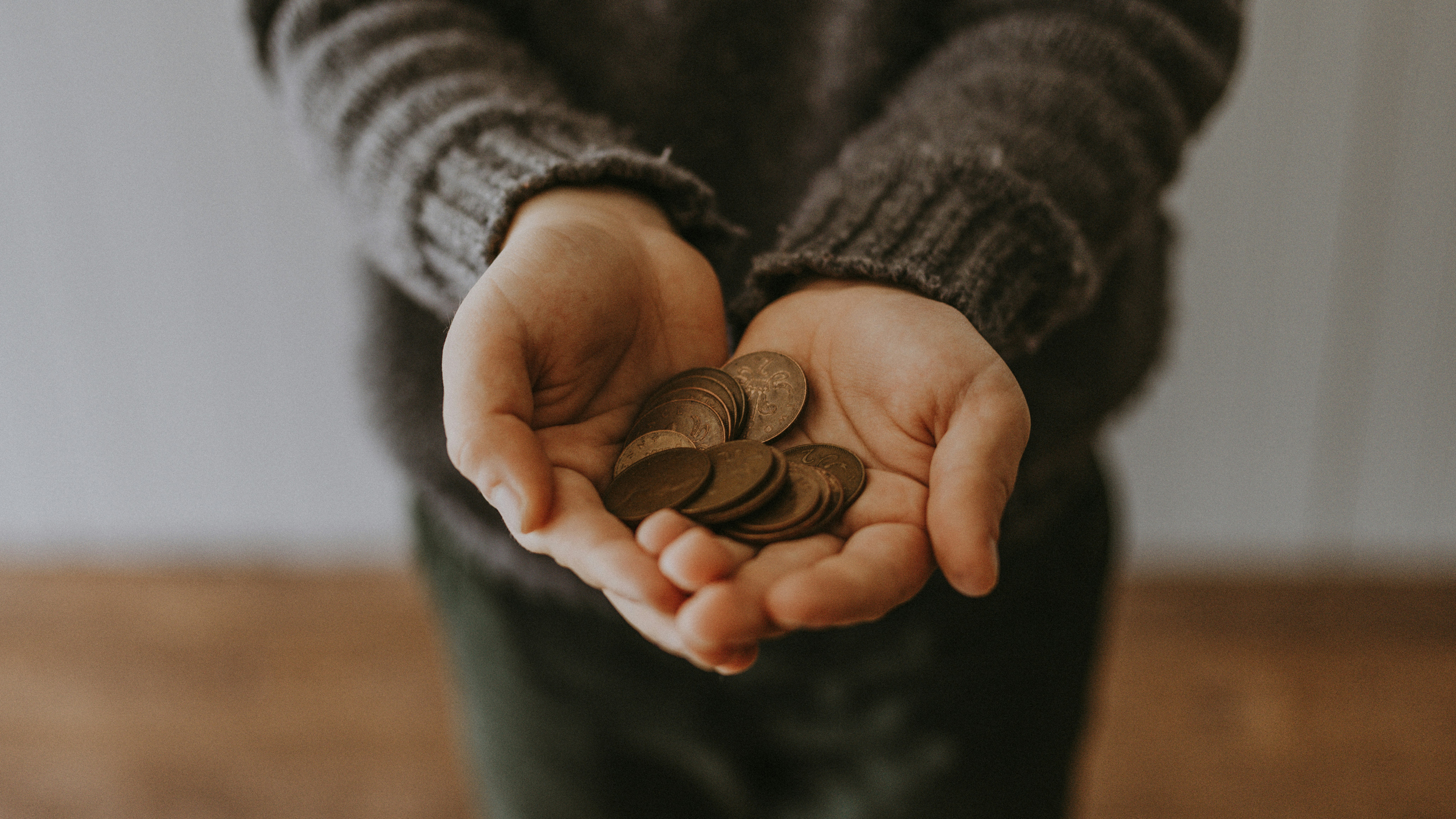 A person holding two hands full of coins. Photo by Annie Spratt on Unsplash