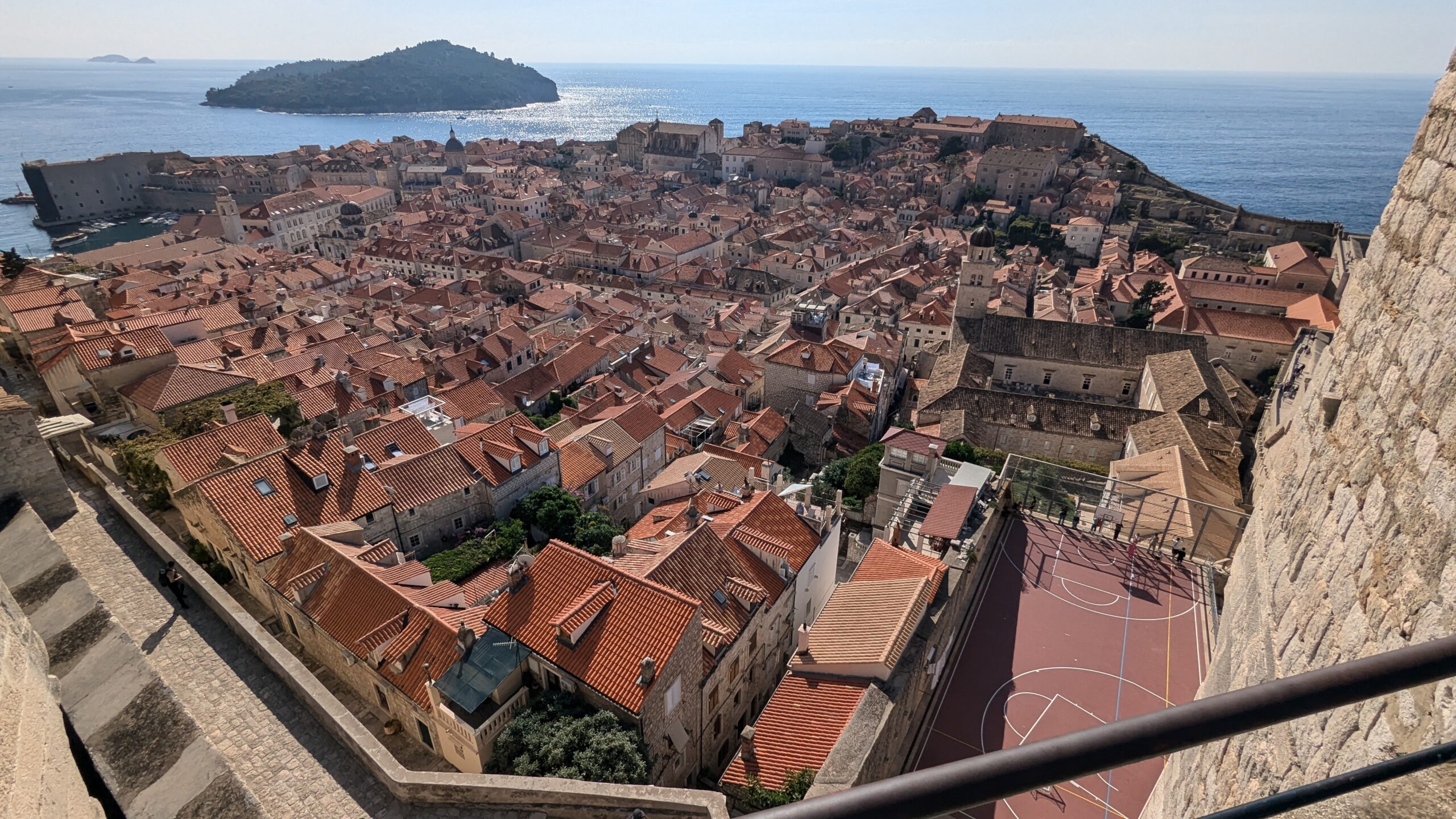 A wide-angle view of the Old town of Dubrovnik with countless red roof tops and the Adriatic Sea with the island Lokrum in the background.